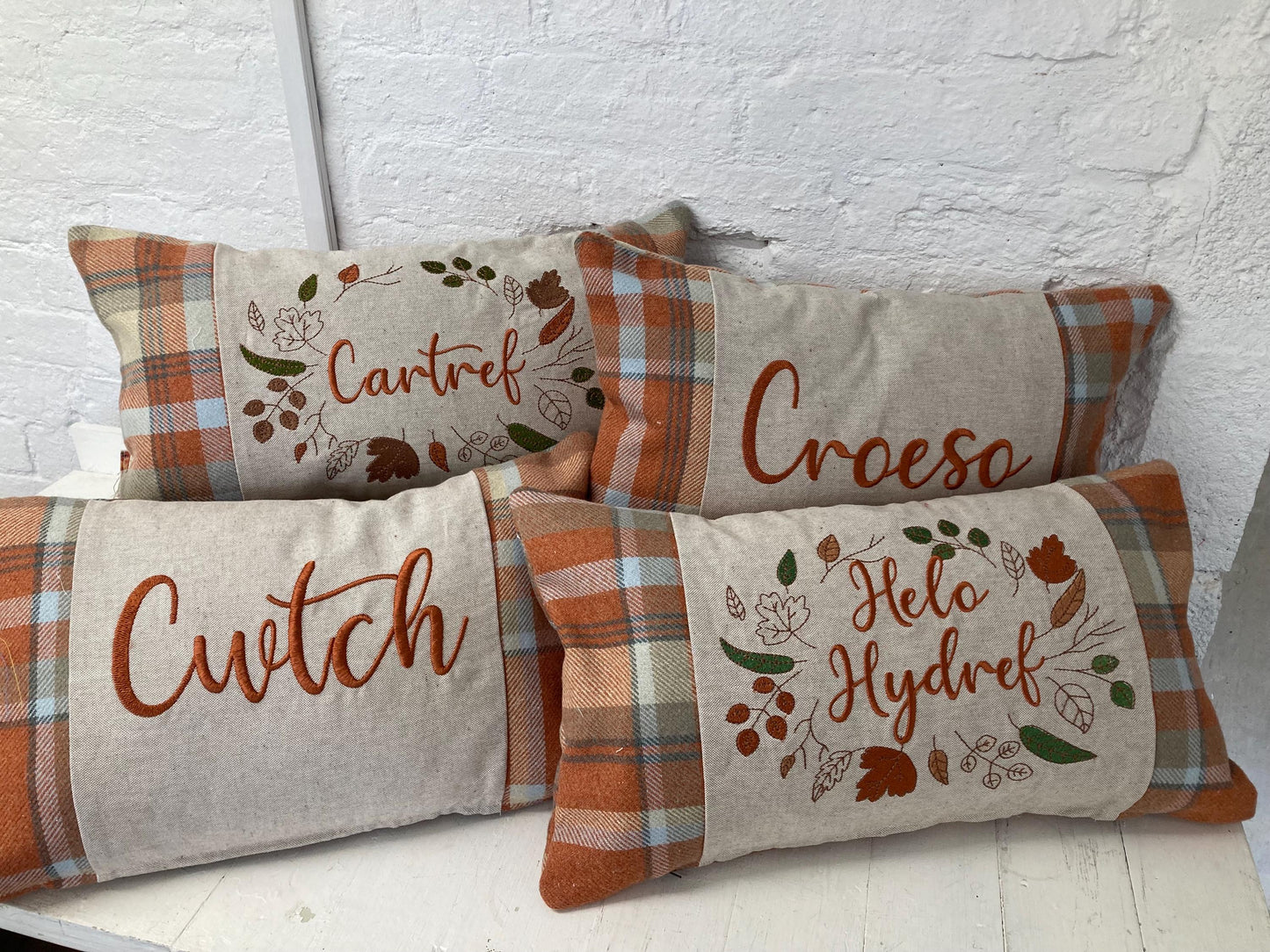 Orange Tartan Cushion with embroidered Helo Hydref (Hello Autumn in Welsh) panel adorned with embroidered leaves.