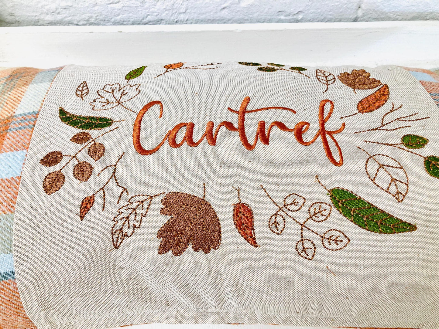 Orange Tartan Cushion with Cartref(Welsh for Home) panel adorned with embroidered leaves.