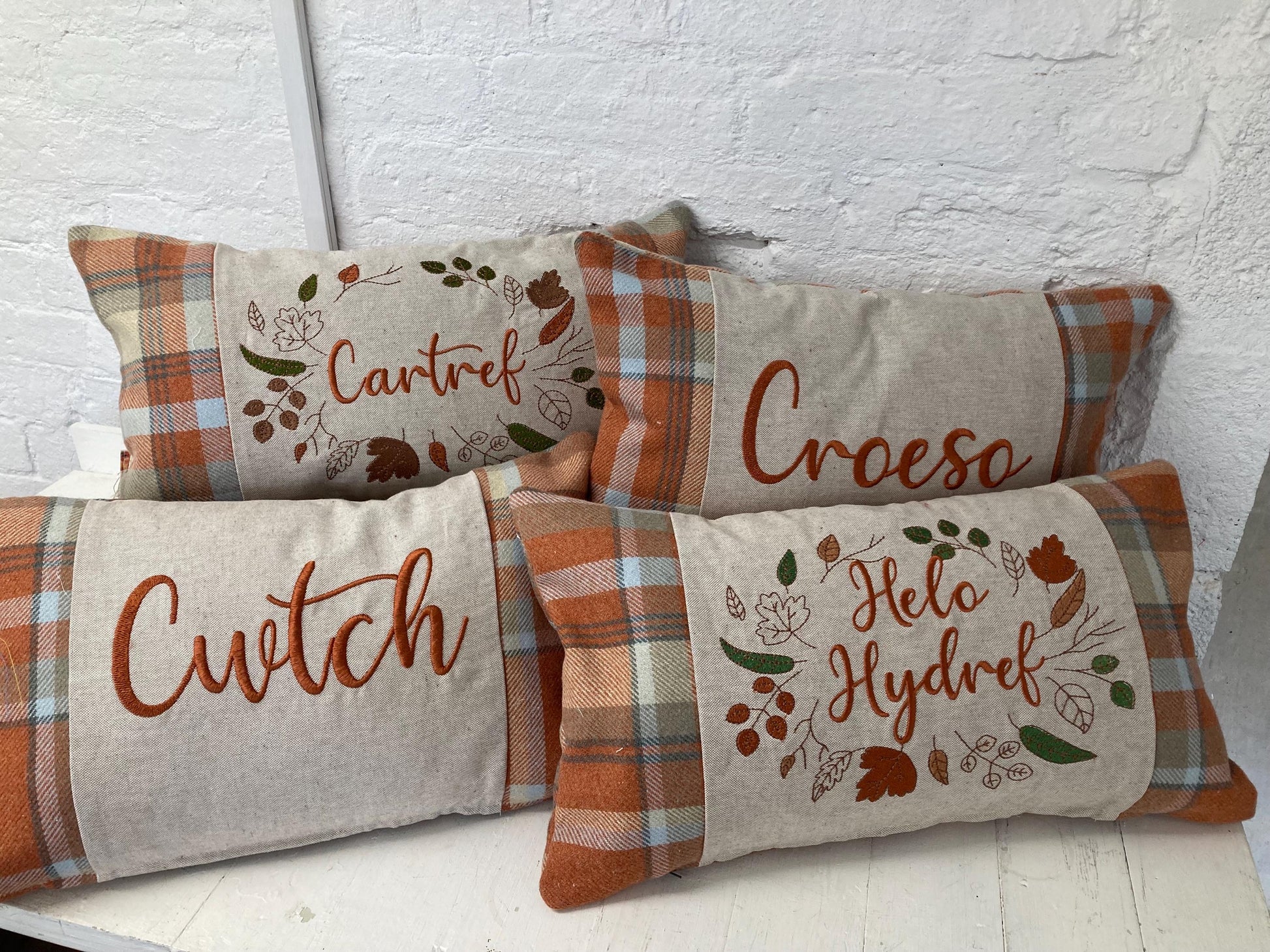 Orange Tartan Cushion with embroidered Helo Hydref (Hello Autumn in Welsh) panel adorned with embroidered leaves.
