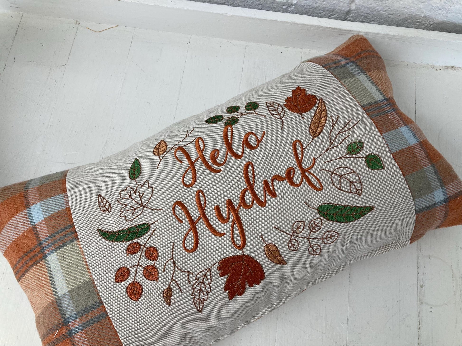 Orange Tartan Cushion with embroidered Helo Hydref (Hello Autumn in Welsh) panel adorned with embroidered leaves.